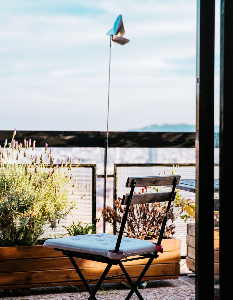Chaise pliante de jardin installée sur un balcon extérieur avec des plantes et une vue dégagée sur la ville, idéale pour les petits espaces